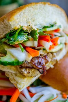 a close up of a sandwich with meat and veggies on it's side