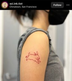 a woman with a tattoo on her arm that has a red outline of a rabbit