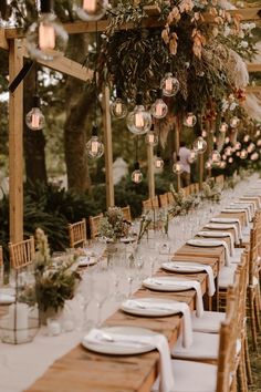 a long table is set up with white plates and place settings for an outdoor dinner