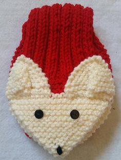 a red and white knitted animal hat with black eyes on it's face