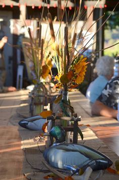 there are many vases with flowers in them on the table at this outdoor event