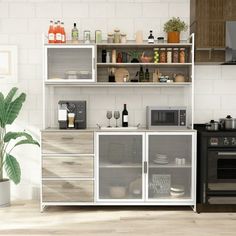 a kitchen with an oven, microwave and other items on the counter top in front of a potted plant