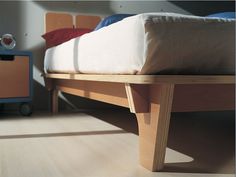 a bed sitting on top of a wooden floor next to a dresser