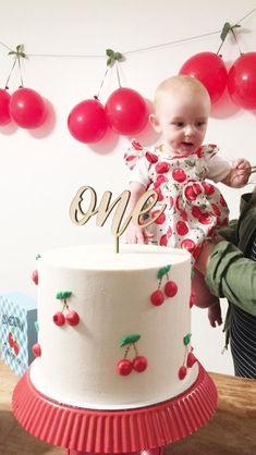 a baby is standing next to a cake