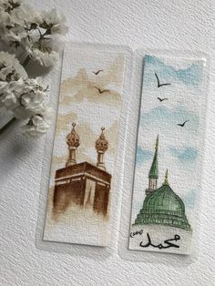 two bookmarks with designs on them sitting next to each other, one has an image of a mosque and the other has a bird