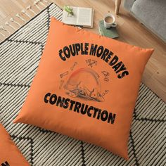 an orange floor pillow that says, couple more days construction on the front and back