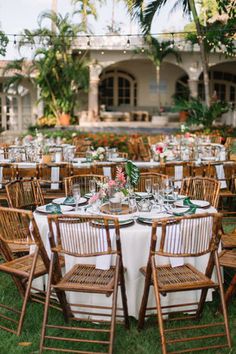 the tables are set up for an outdoor wedding reception in front of a tropical garden