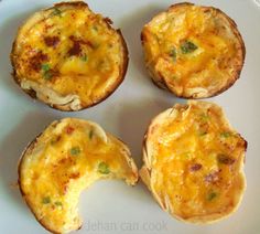 four mini quiches on a white plate with green onions and cheese in the middle