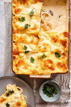 a casserole dish with cheese and parsley on top next to two plates