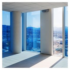 an empty room with large windows overlooking the city and mountains in the distance, is shown