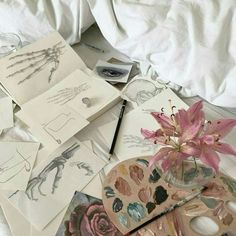 some drawings and flowers are laying on the bed