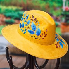 Mexican artisan Ana Cristina handcrafts a stunning fedora in a striking honey hue that will take your breath away. She expertly hand-paints leaf motifs in shades of Caribbean blue, cerulean and light red for a hat that makes an absolute and everlasting fashion statement. Hat Burning, Blue Foliage, Brown Accessories, Poncho Shawl, Caribbean Blue, Paint Projects, Leaf Motif, Mens Jewelry Necklace