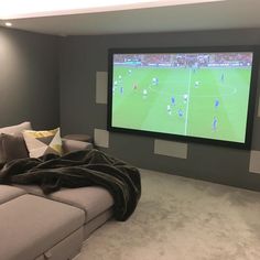 a living room with a large screen tv on the wall and a couch in front of it