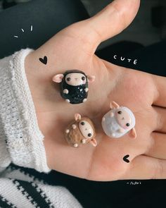 three small figurines in the palm of someone's hand, one is wearing a sweater