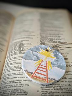 a book with an ornament on top of it and a ladder to the sky