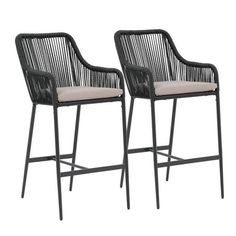 two black wicker barstools with beige cushions on white backgrouds