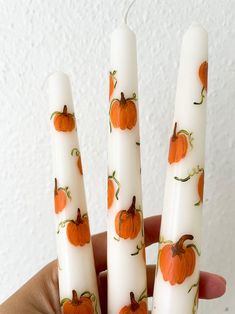 three white candles with pumpkins painted on them