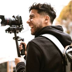 a man is smiling while holding a camera