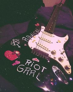 an electric guitar with the words riot girl written on it's body and decorated with hearts