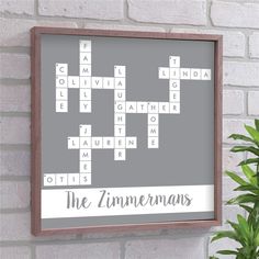 a crossword puzzle is hanging on the wall next to a potted green plant