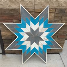 a blue and white wooden star on the side of a building next to a brick wall