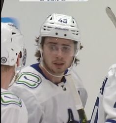 two hockey players talking to each other in front of an ad for the vancouver maples