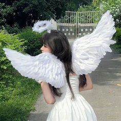 a woman in a white dress with angel wings on her back and long black hair