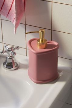 a pink soap dispenser sitting on top of a white sink next to a pink towel