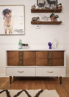 a white and brown dresser sitting on top of a hard wood floor next to a wall