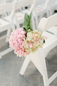 a bouquet of pink and green flowers sitting on top of a white chair next to other chairs