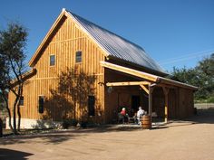 two people sitting at a table in front of a large wooden building with a metal roof