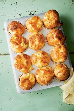 muffins with cheese are sitting on a baking tray next to a yellow napkin