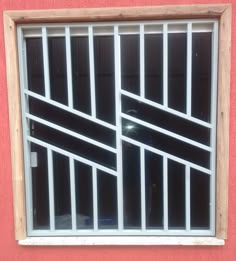 an open window with bars on the side of it in front of a red wall