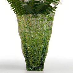 a green vase filled with flowers and greenery