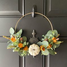 a wreath with flowers and leaves hanging on a door