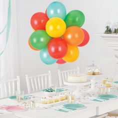 a bunch of balloons that are in the air above a table with cake and cupcakes