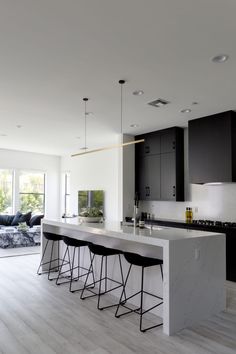 a modern kitchen with black and white appliances, marble countertops and bar stools