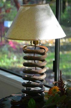 a lamp sitting on top of a table next to a window sill with flowers in front of it