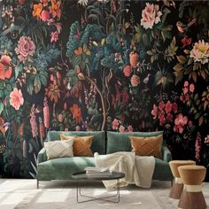 a green couch sitting in front of a floral wall mural