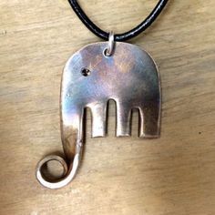 an elephant shaped pendant is hanging from a leather cord