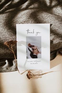 a thank you card is placed on top of a t - shirt with dried flowers