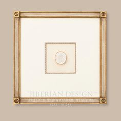 a white and gold frame with a button in it's center on the wall