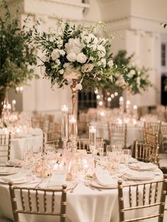 an elegant wedding reception with tall centerpieces and white flowers on the top table