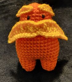 an orange crocheted stuffed animal wearing a yellow hat