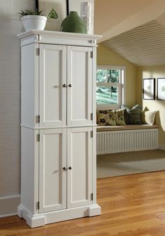 a tall white cabinet sitting on top of a hard wood floor