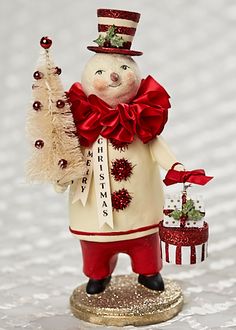 a snowman figurine holding a christmas tree