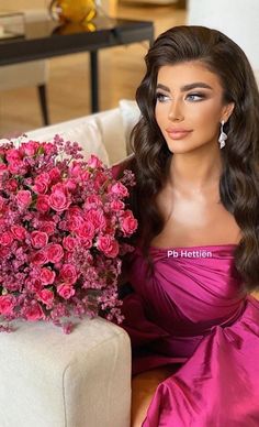 a barbie doll sitting on a couch next to a bouquet of pink roses in her hand