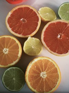 oranges, limes and grapefruit cut in half on a white surface