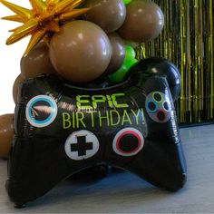 a black video game controller with balloons and streamers