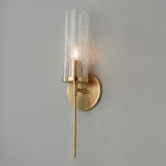 a gold wall light with a glass shade on the side and a single candle in the middle